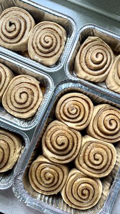 four trays filled with cinnamon rolls sitting on top of a counter