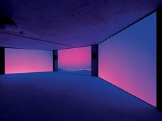 an empty room with pink and blue lighting on the walls, in front of mountains