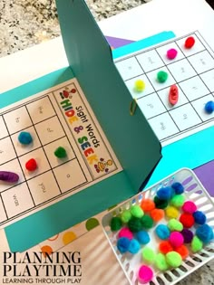 a paper board game with pom poms on it and a play time box