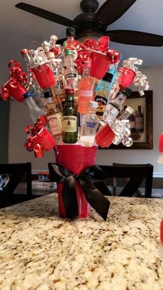 a red vase filled with liquor bottles on top of a table