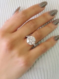 a woman's hand wearing a ring with a diamond on it and two fingers