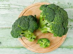 two pieces of broccoli on a wooden plate