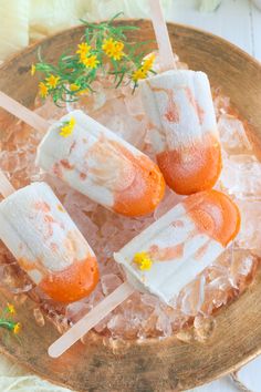 marshmallow pops with orange and white toppings on ice in a wooden bowl