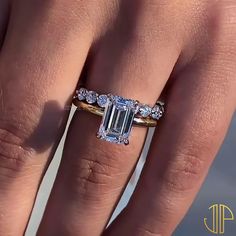 a woman's hand with a ring on it and an emerald stone in the middle