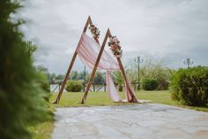 an outdoor ceremony setup with pink and white draping on the grass, decorated with flowers