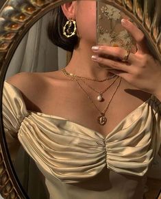 a woman taking a selfie in front of a mirror with jewelry on her neck