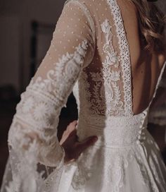 the back of a woman's wedding dress with sheer sleeves and beaded details