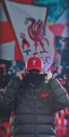 a man wearing a red hat and black puffer jacket in front of a flag