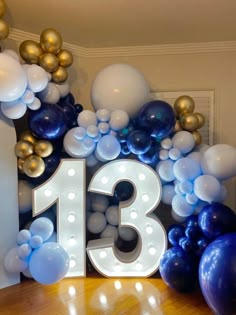 the number thirteen is surrounded by balloons in blue and gold colors, as well as an arch