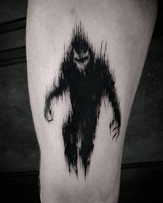 a black and white photo of a man's leg with an inked creature on it