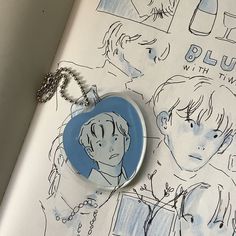 a blue and white keychain sitting on top of a book next to a drawing