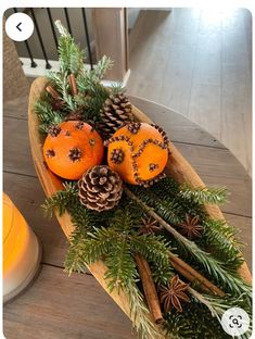 a wooden boat filled with pine cones and oranges on top of a wood table