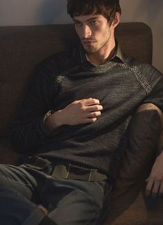 a young man sitting on top of a brown couch