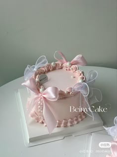 a pink cake decorated with bows and pearls