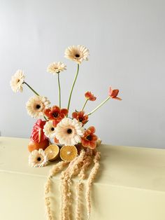 an arrangement of flowers in a vase on a table with beads and other items around it