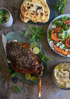 an assortment of food on plates including meat, salad and pita bread