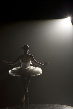 a ballerina is standing in the spotlight