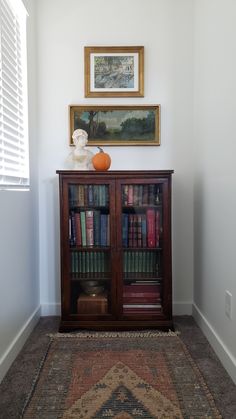 a bookshelf with many books in it and a painting on the wall behind it