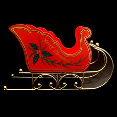 a red and gold sleigh with holly decorations on the sides, sitting in front of a black background