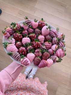 a person holding a plate full of strawberries and chocolate covered strawberries in the shape of hearts