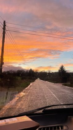 the sun is setting over an empty road with power lines in the distance and telephone poles on either side