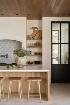 a kitchen with two stools in front of the counter and an oven on the wall