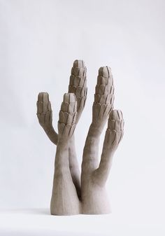 two hands made out of clay on a white surface with one hand reaching up to the ground