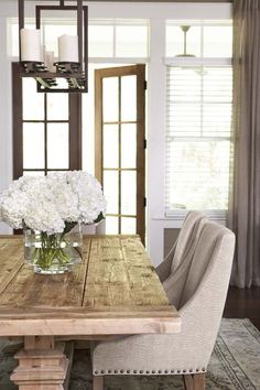 a dining room table with chairs and flowers in a vase on it's centerpiece