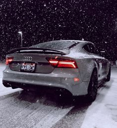 an audi car is driving down the road in the snow with its tail lights on