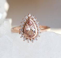 an engagement ring with a pear shaped morganite surrounded by diamonds