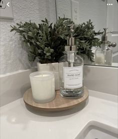 a bottle of hand soap sitting on top of a wooden tray next to a candle