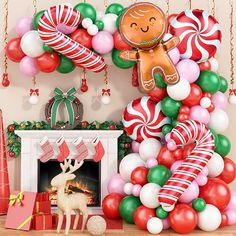 a christmas tree decorated with balloons, candy canes and gingerbread man in front of a fireplace