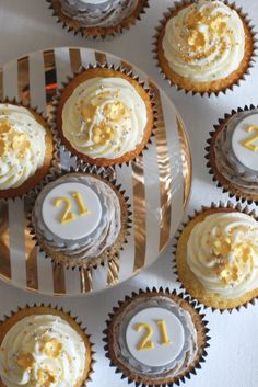 several cupcakes with white frosting and yellow sprinkles are arranged on a plate