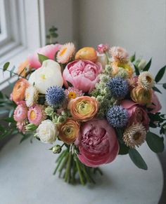 a bouquet of flowers sitting on top of a table next to a window sill