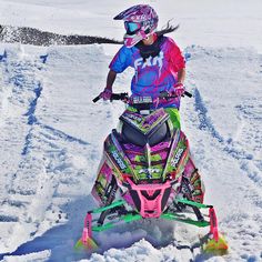 a woman riding on the back of a snowmobile down a snow covered ski slope