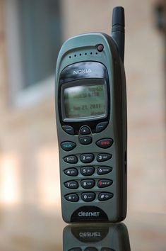 an old cell phone sitting on top of a glass table in front of a building