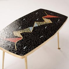 a black and gold mosaic table sitting on top of a white floor