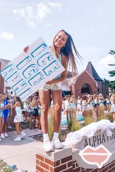 a girl is holding up a sign in front of a group of other people outside