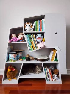 a book shelf with several books and stuffed animals on it in the corner of a room