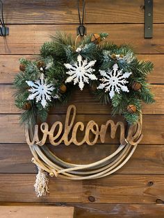 a welcome sign hanging from the side of a wooden wall with snowflakes on it