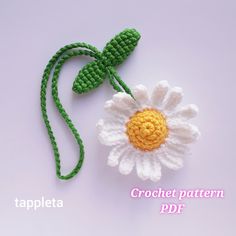 a crocheted flower is attached to a green string on a white background with the words tappleta written below it