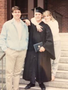 two men and a woman in graduation gowns posing for a photo on the steps