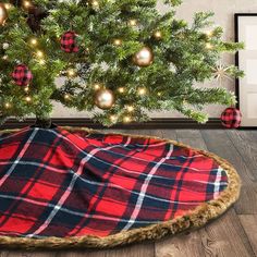 a christmas tree in the corner of a room with a red and black plaid blanket on it