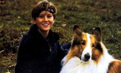 a boy sitting next to a brown and white dog on top of a grass covered field