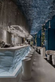 the interior of a modern restaurant with blue and white walls, long tables and stools