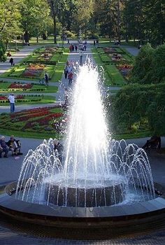 a fountain in the middle of a park filled with people