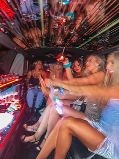 a group of women sitting in the back of a limo with drinks on each side