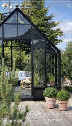 a small black house sitting on top of a wooden deck next to potted plants