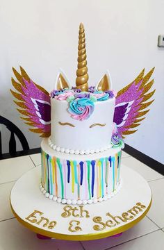 a birthday cake decorated with an unicorn's head and rainbow streamers on top