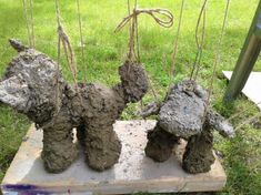 three teddy bears made out of mud sitting on a piece of wood